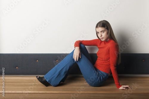 Beautiful, blond, scandinavian, kaukasian girl in orange sweater and blue jeans, cowboy trousers photo