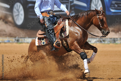 Fototapeta Naklejka Na Ścianę i Meble -  A close up view of a rider sliding the horse in the dirt