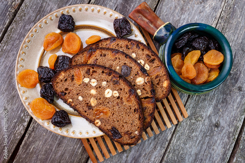 Sliced rye bread with prunes, dried apricots and hazelnut on old rustic table. Top view.