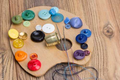 buttons, thimble, needle and thread on the palette