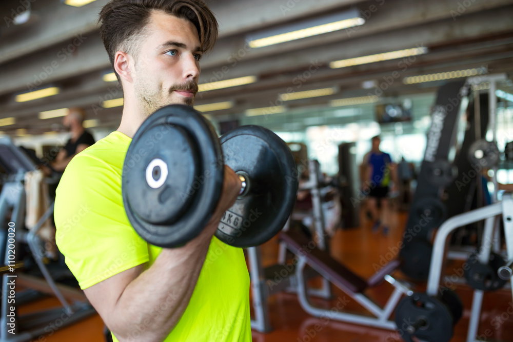 Handsome young man doing muscular exercise in gym. Handsome young man doing muscular exercise in gym.