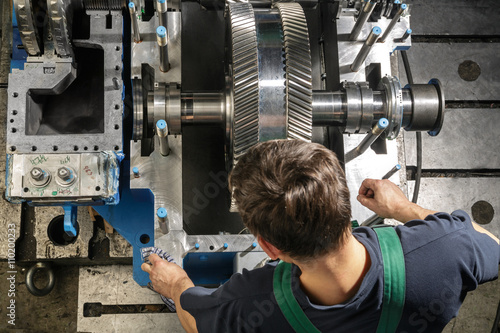 Working people with a small steam turbine. Metal gears. Gear wheels of the engine.