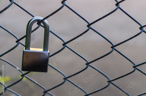 Silver metal lock sticked on grate fence.