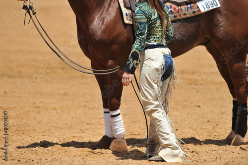 Fragment of the western style rider with cowboy chaps and her horse