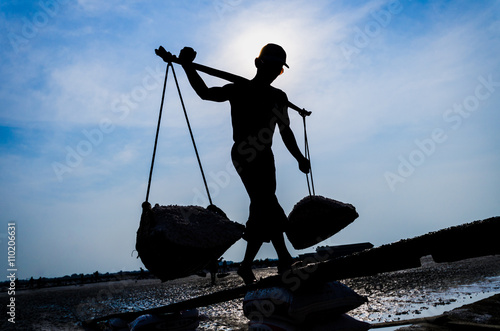 Silhouette of a man working on salt field.