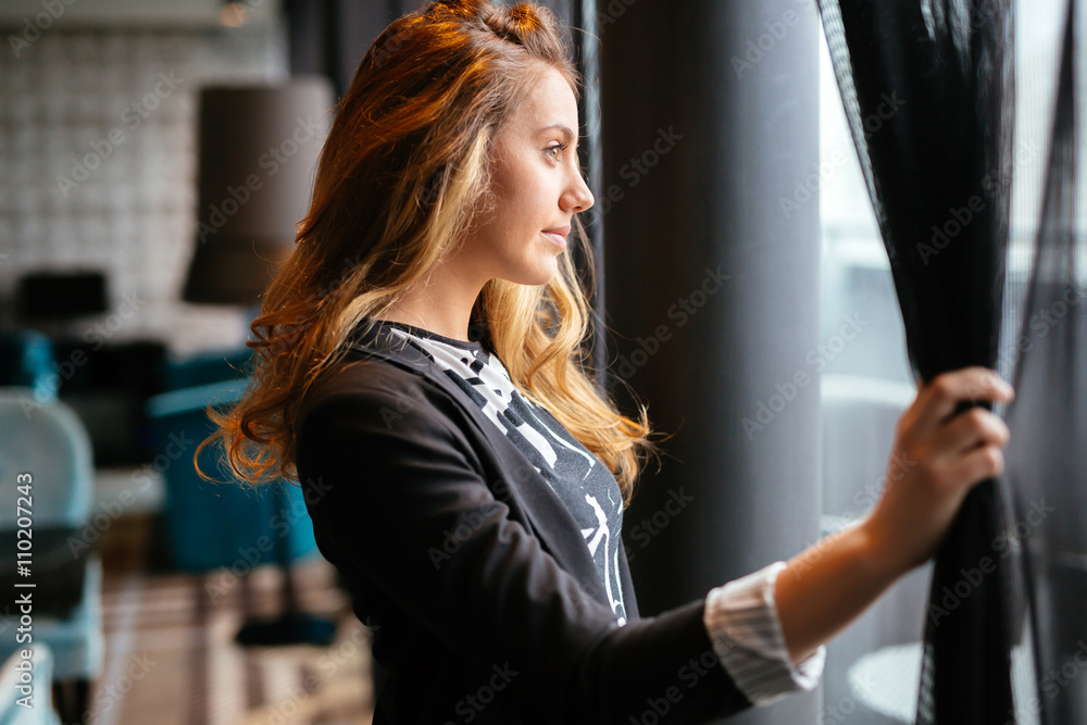 Pensive beautiful businesswoman looking through window