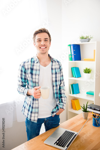 Handsome smiling man having break and drinking coffee photo