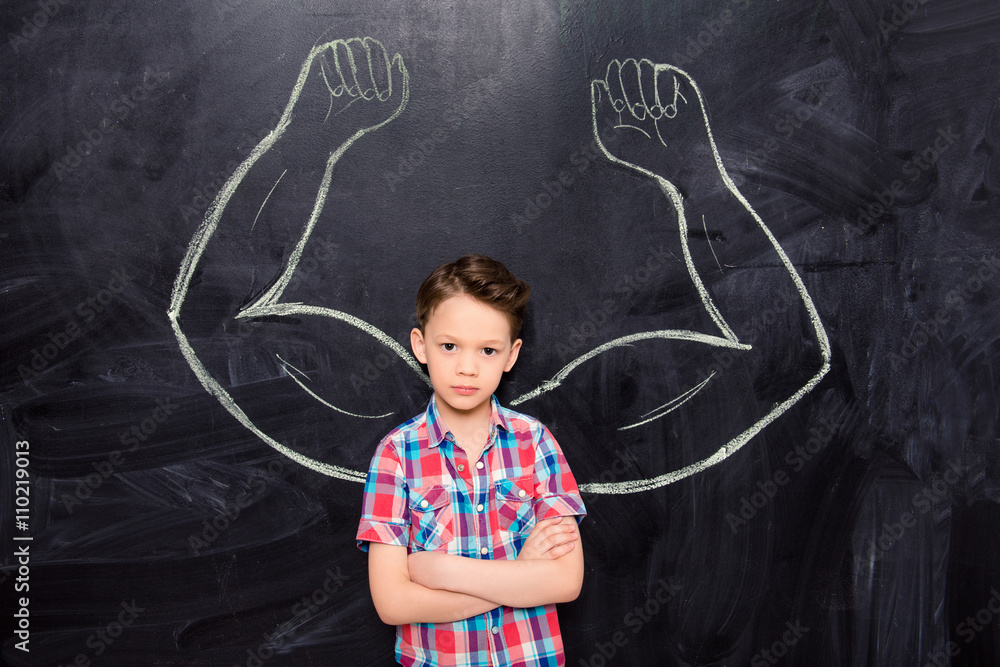 Little boy on backgroung of blackboard with drawn muscles