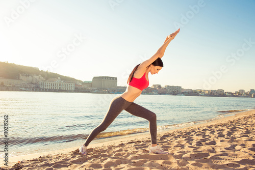 Young slim fit woman doing exercises on open air