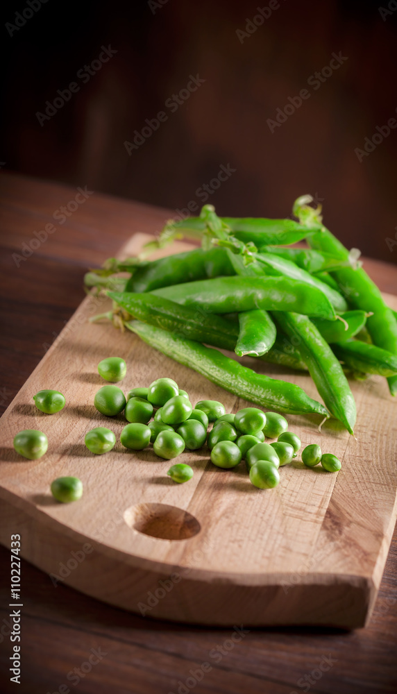 Peas group on cutting board and wooden table on dark backgound Peas group on cutting board and wooden table on dark backgound