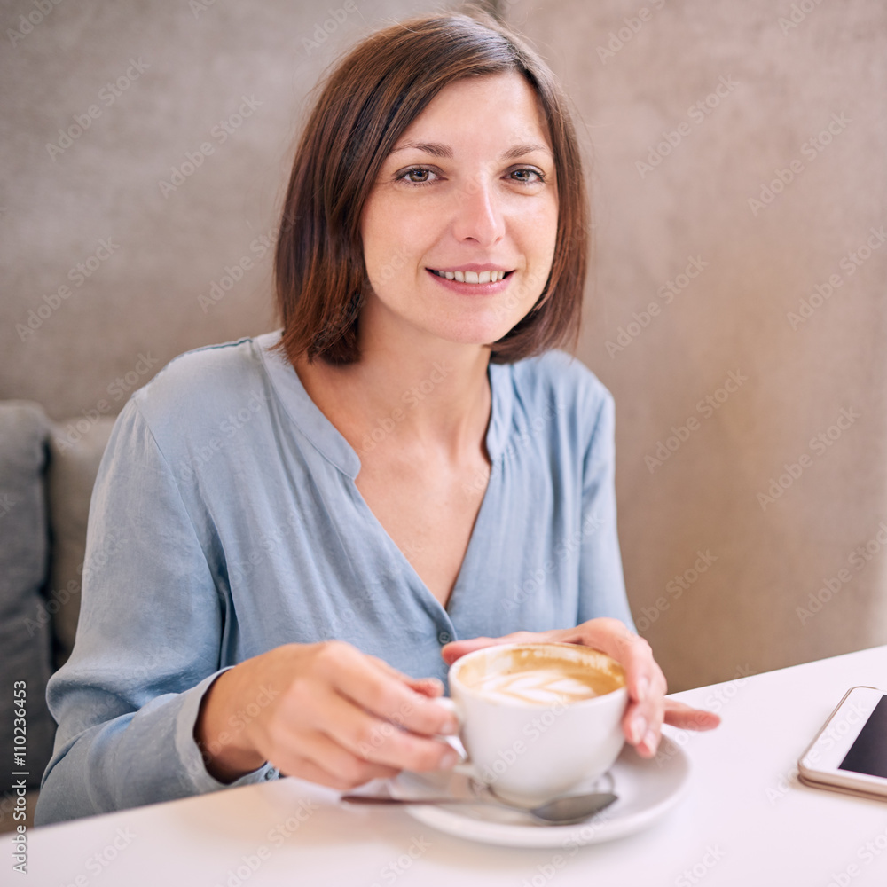 woman smiling at camera with coffee in her hands woman smiling at camera with coffee in her hands