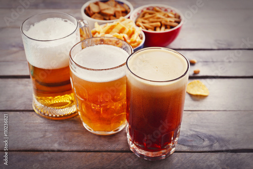 Various types of beer and snacks on wooden table. Retro stylization