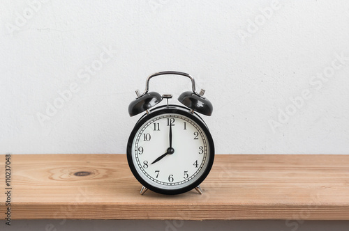 Vintage alarm clock on wood shelf ( alarm clock show 8 o`clock
