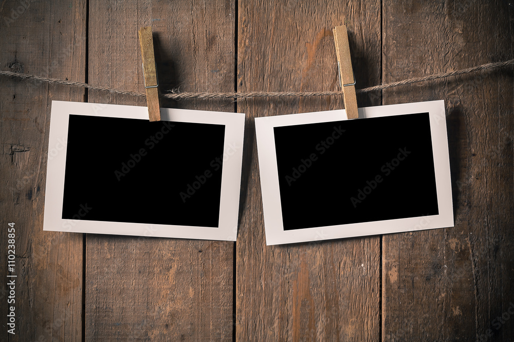 Fototapeta premium Blank Old Photo Frame Hanging on a Rope By Clothespin on.Wood Ba