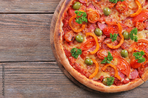 Tasty pizza with sausage and vegetables on wooden table background