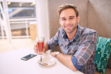 Good looking man looks straight at camera sitting in cafe