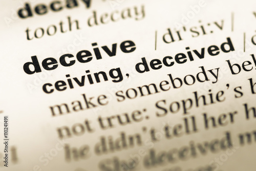 Close up of old English dictionary page with word deceive
