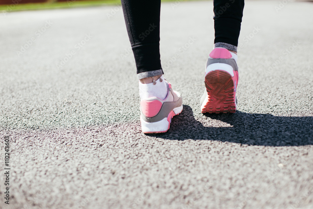 Runner feet running on road closeup on shoe. woman fitness jog workout welness concept.