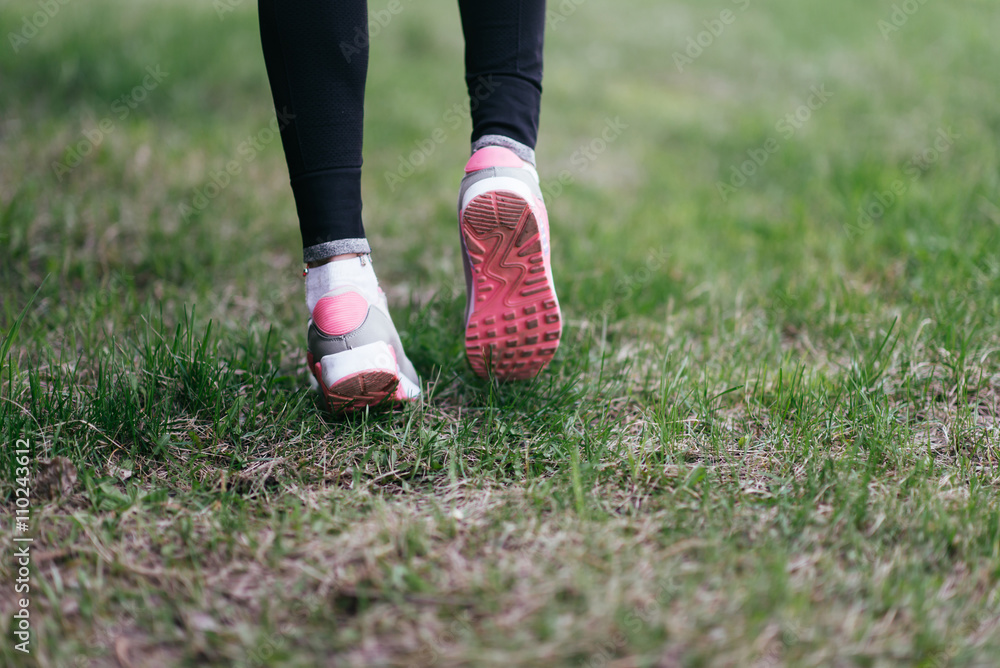 Runner feet running on road closeup on shoe. woman fitness jog workout welness concept.