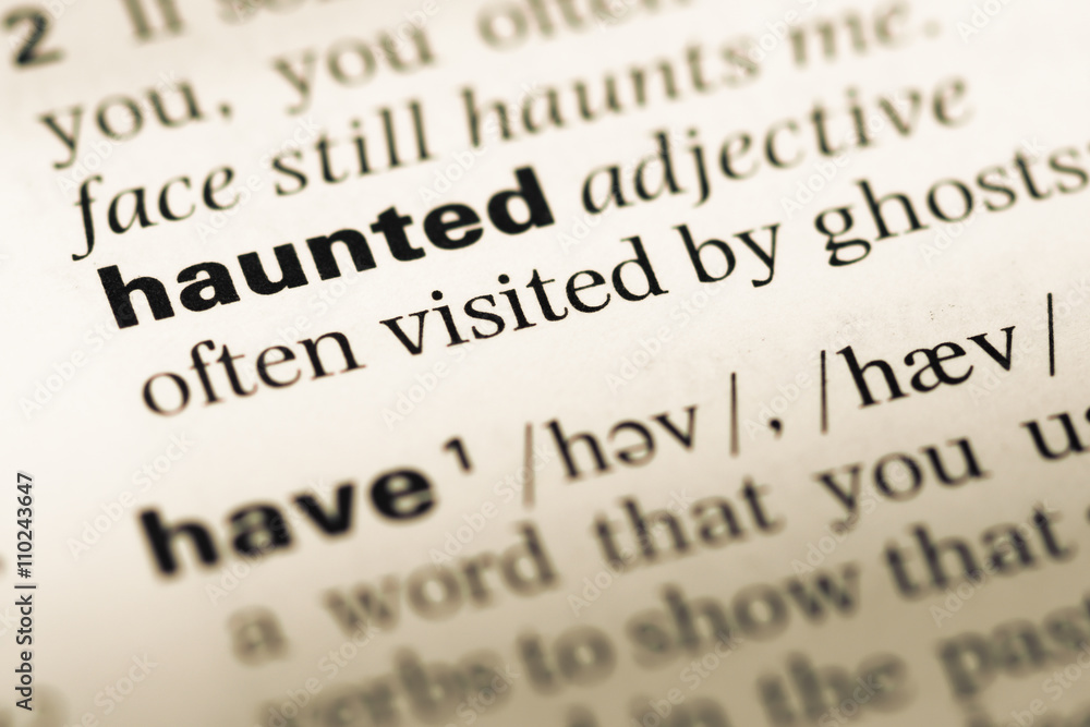 Close up of old English dictionary page with word haunted Close up of old English dictionary page with word haunted