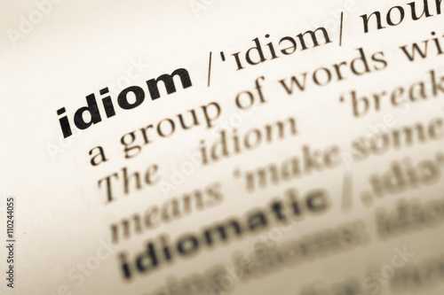 Foto Close up of old English dictionary page with word idiom