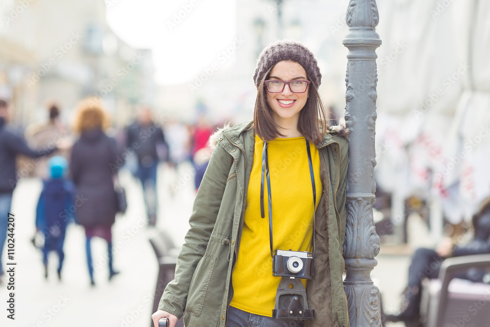 Portrait of a beautiful young hipster girl with an old-fashion camera looking at camera and smiling