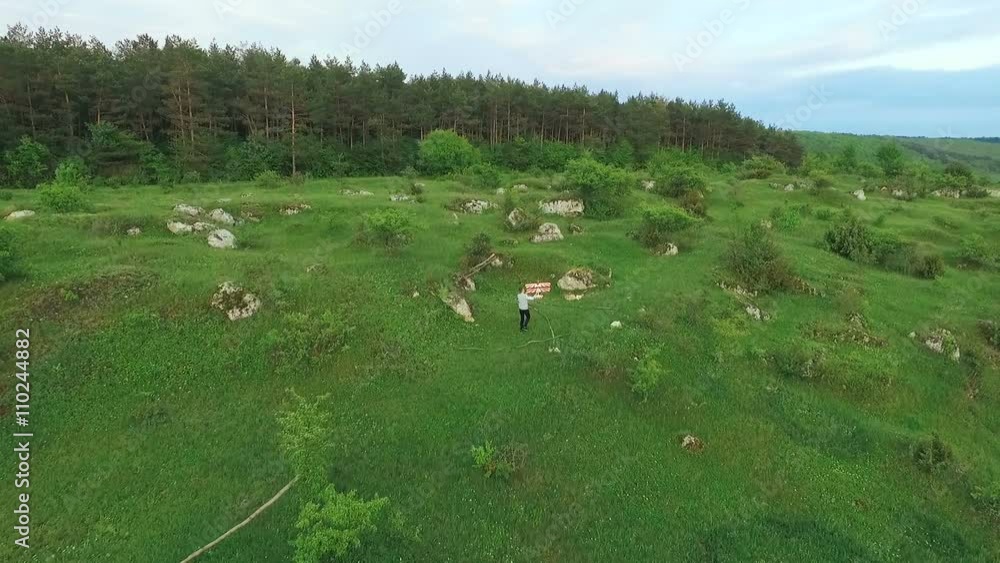Aerial view of young boy goes with toy airplane on the green mountains Aerial view of young boy goes with toy airplane on the green mountains