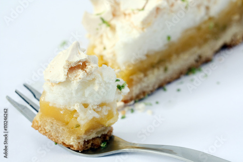 eating bite of piece of lemon meringue pie, tart, decorated with lime, isolated 