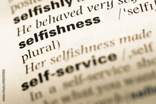 Close up of old English dictionary page with word selfishness