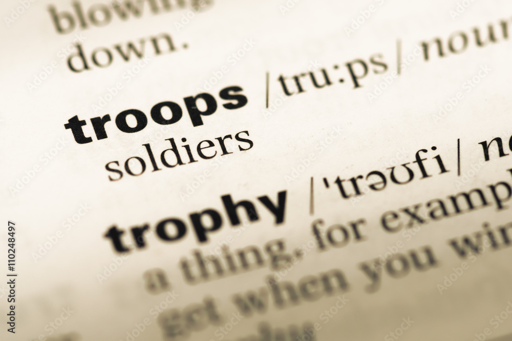 Close up of old English dictionary page with word troops Close up of old English dictionary page with word troops