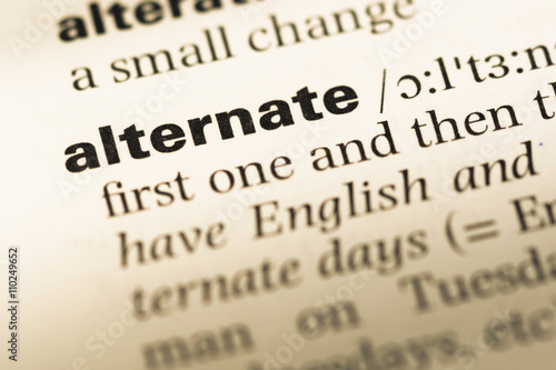 Foto Close up of old English dictionary page with word alternate