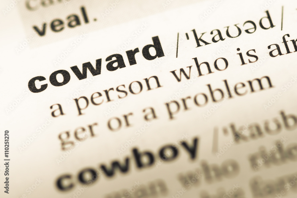 Close up of old English dictionary page with word coward Close up of old English dictionary page with word coward