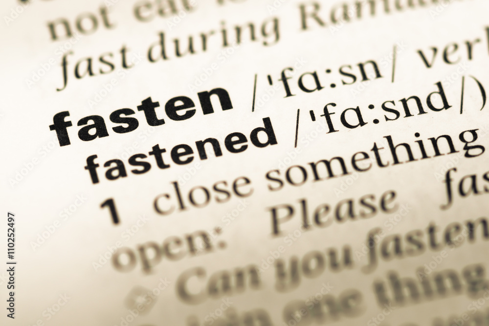 Close up of old English dictionary page with word fasten Close up of old English dictionary page with word fasten