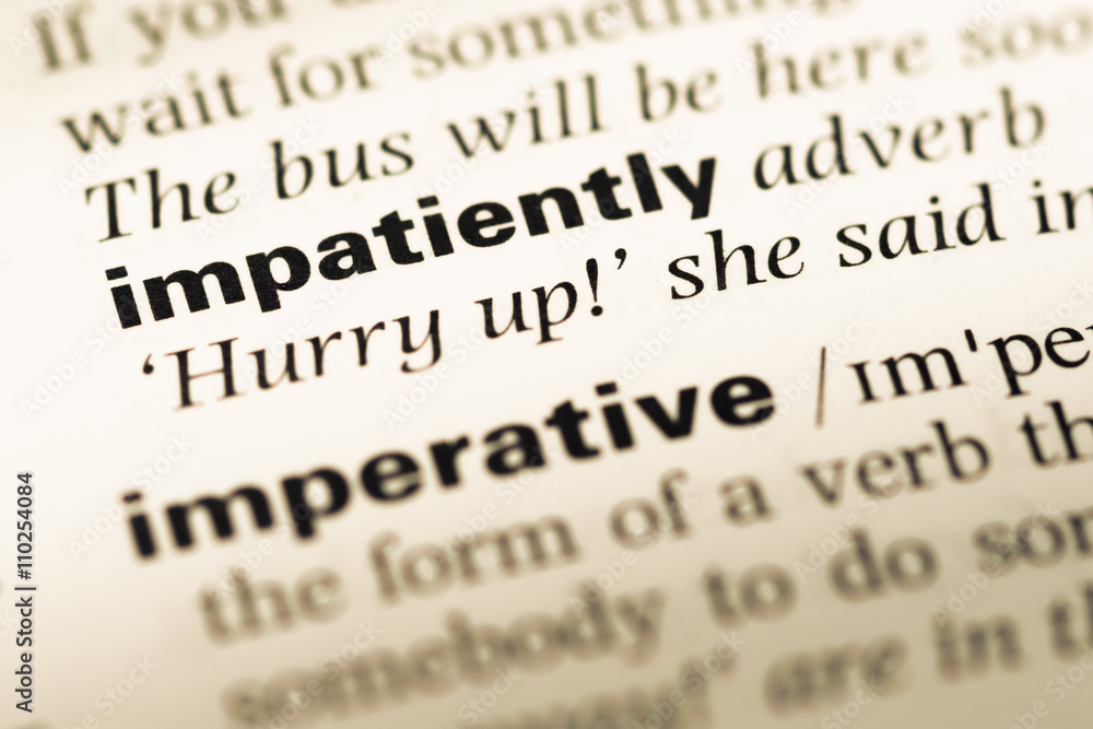 Close up of old English dictionary page with word impatiently Close up of old English dictionary page with word impatiently