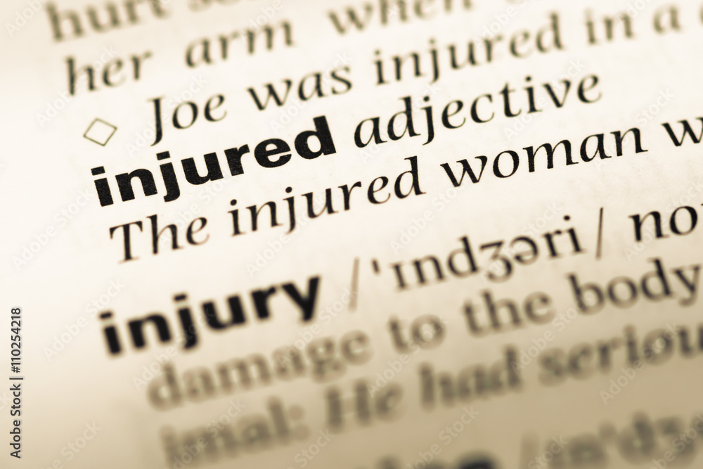 Close up of old English dictionary page with word injured Close up of old English dictionary page with word injured