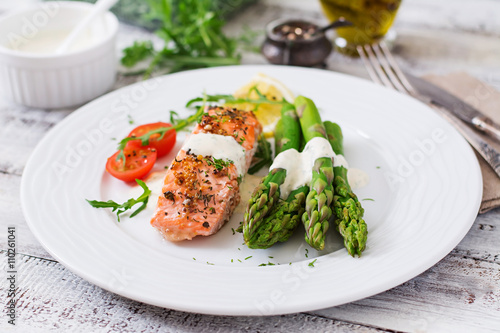 Baked salmon garnished with asparagus and tomatoes with herbs