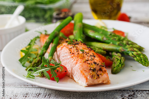Photo Baked salmon garnished with asparagus and tomatoes with herbs