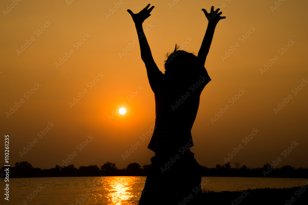 Fototapeta premium Little boy jumping before the sunset silhouette
