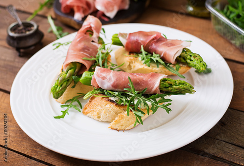 Toasts (sandwich) with asparagus, arugula and prosciutto