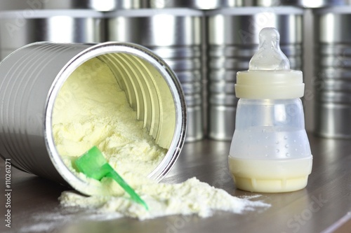 Baby bottle with many boxes of infant milk. One boxe is opened.