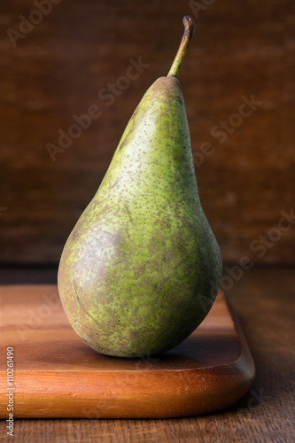 Ripe pear on wooden cutting board