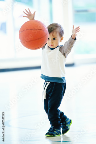 Cute adorable little small white Caucasian child toddler boy playing with ball in gym, having fun, healthy lifestyle childhood concept