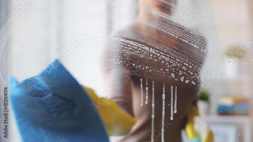 woman in gloves cleaning window with rag and spray