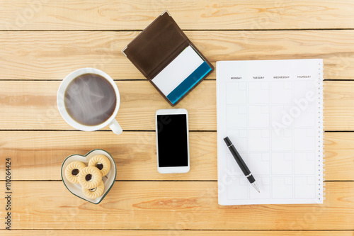 Top view mobile phone with blank note book with pen, hot coffee