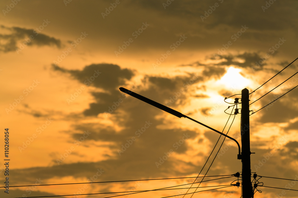 Sunset and dark sky background with silhouette of electric pole and wire 
