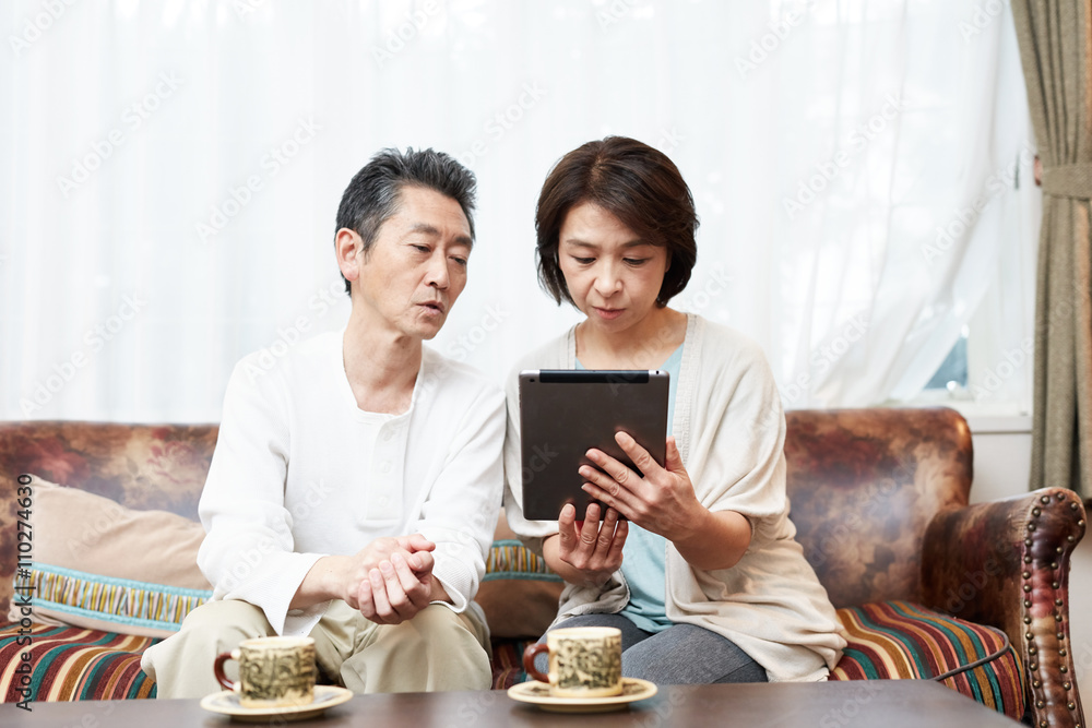 タブレットを使う中年夫婦 タブレットを使う中年夫婦