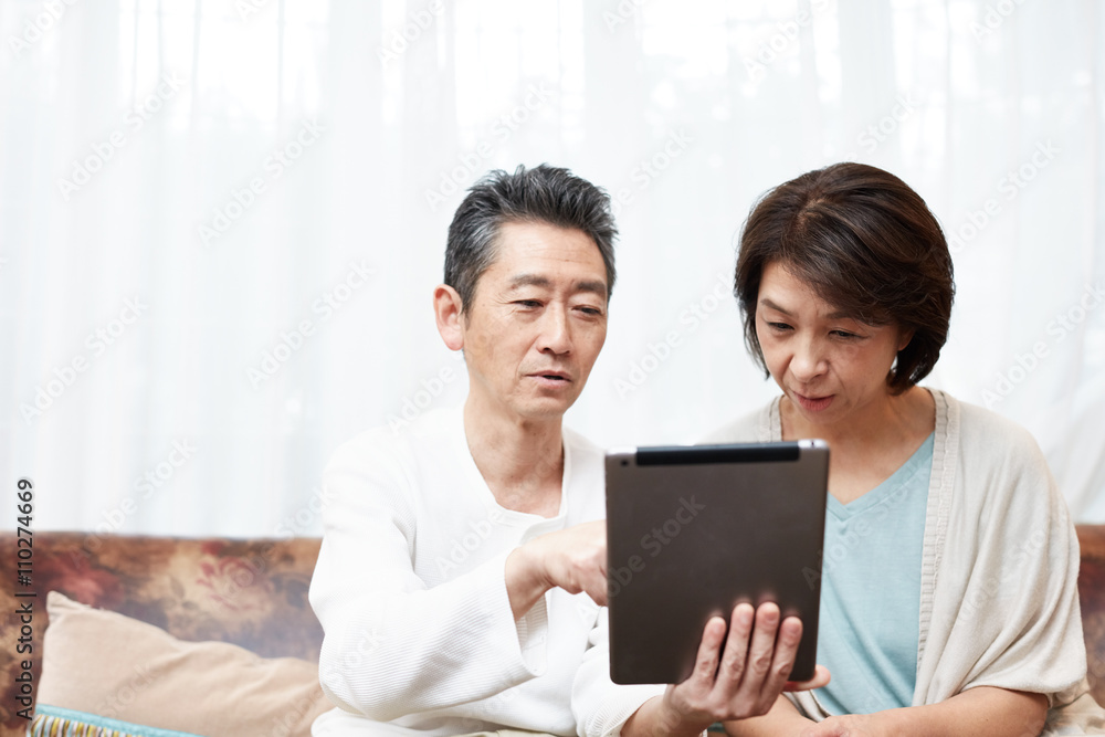 タブレットを使う中年夫婦 タブレットを使う中年夫婦