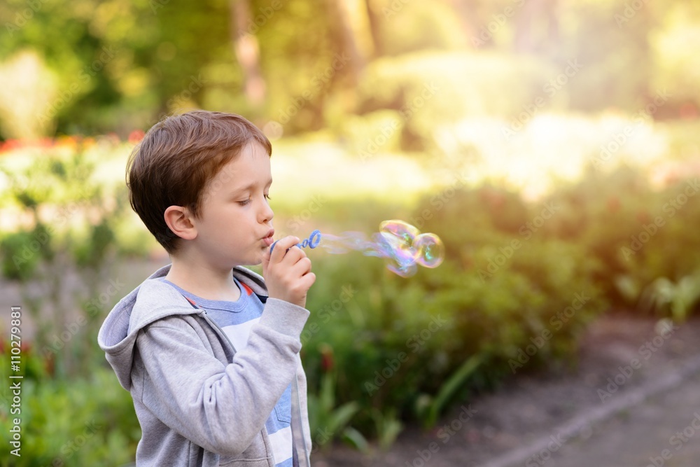 Little boy blowing soap bubbles in the park Little boy blowing soap bubbles in the park