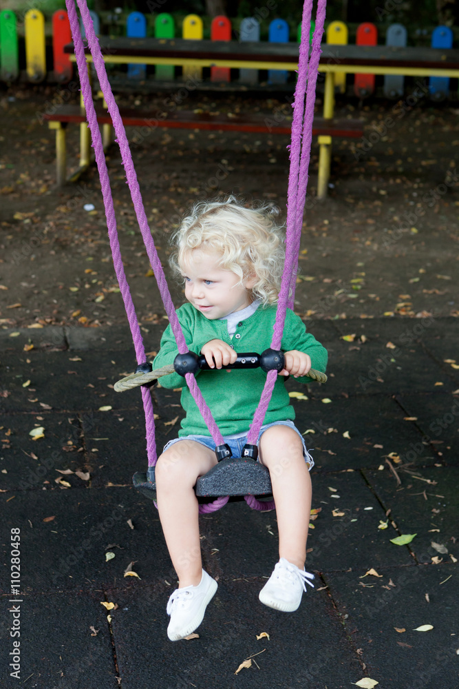 Funny blond boy riding on a swing Funny blond boy riding on a swing