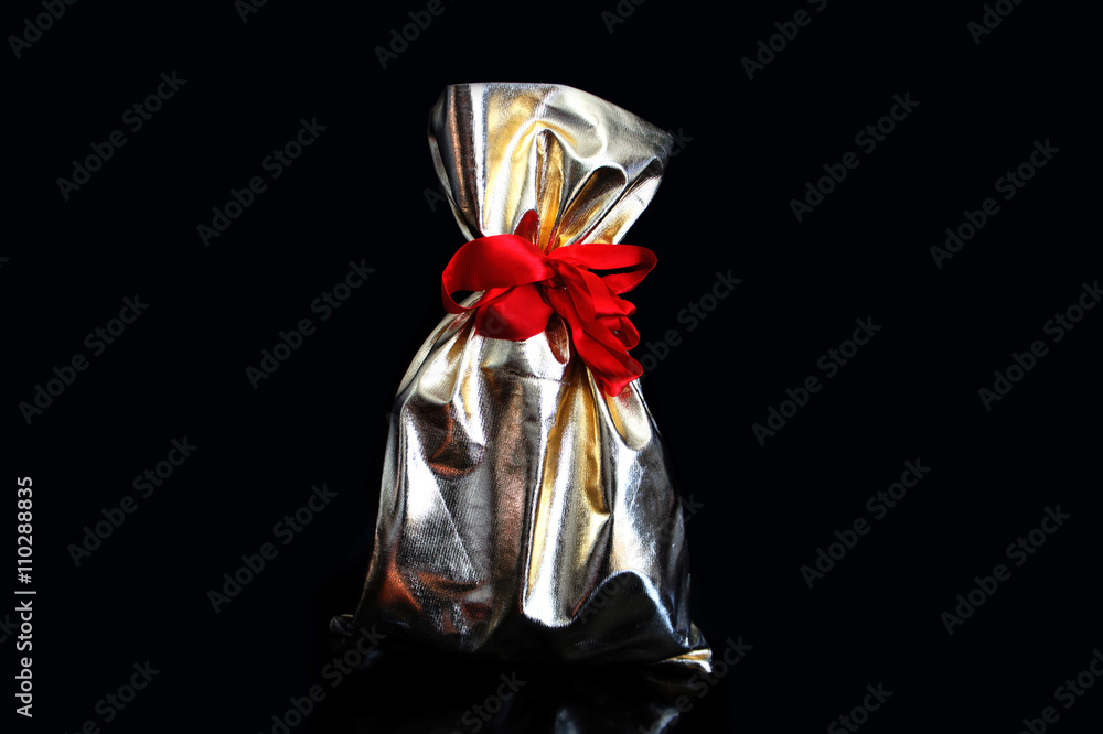 Golden gift bags tied with a red ribbon on a black background